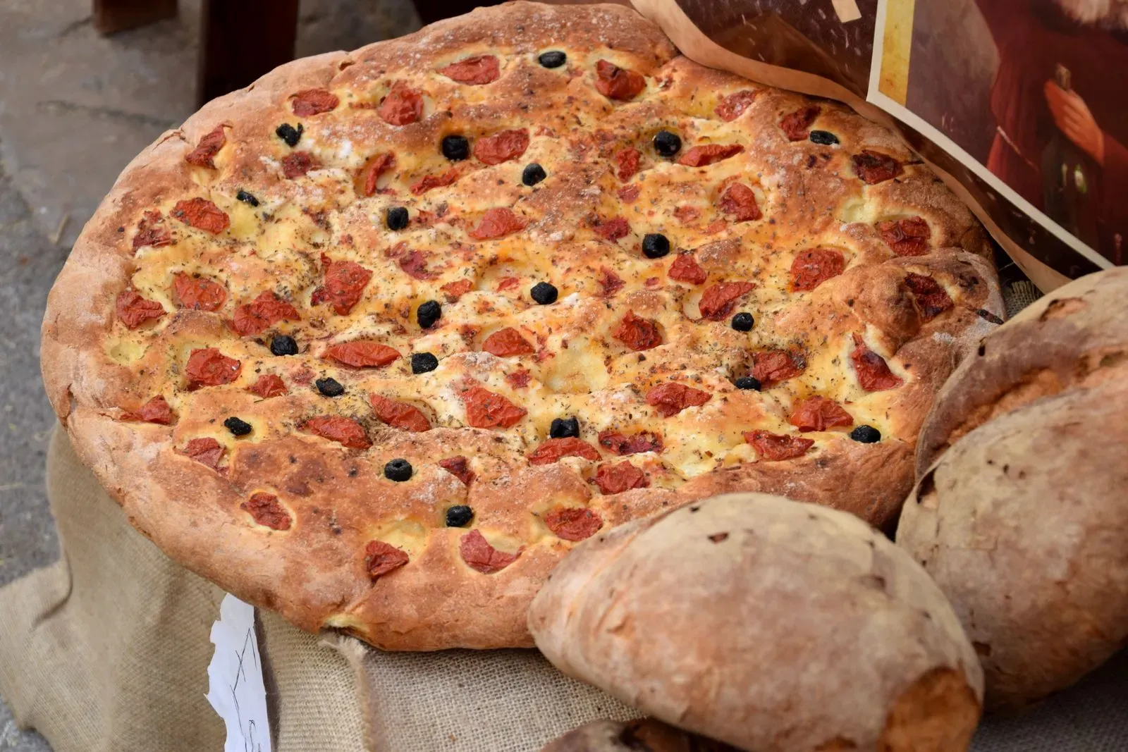 A round focaccia barese topped with cherry tomatoes and black olives